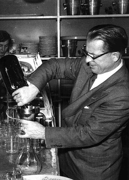 Anton Karas hinter der Bar, wie er ein Getränk einschenkt, schwarz-weiß