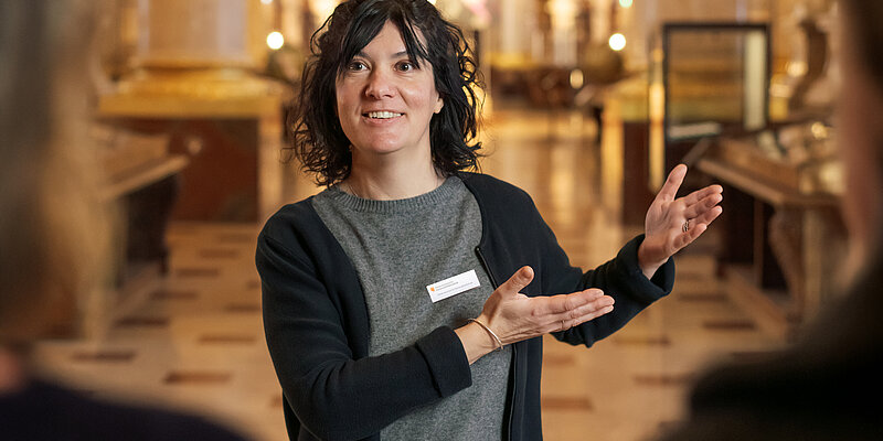 Foto von Person in Marmorsaal die "Willkommen" in Gebärdensprache zeigt.