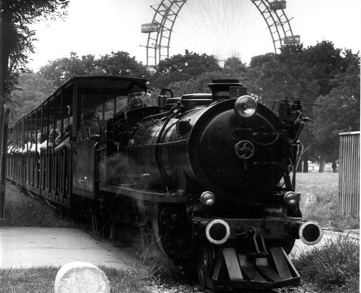 Schwarz-Weiß Foto einer Bahn, die auf Schienen fährt. 