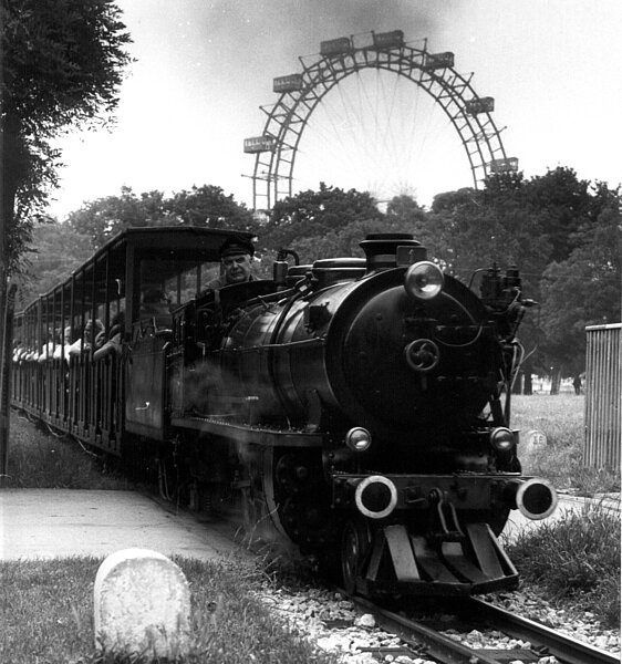 Schwarz-Weiß Foto einer Bahn, die auf Schienen fährt. 